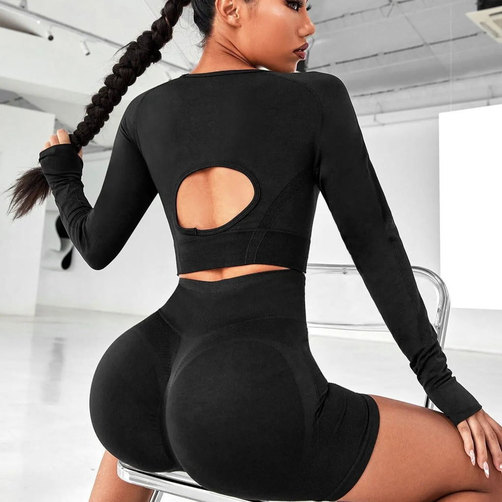 Women's black yoga set comprising a long sleeve top and high-waist trousers laid flat.