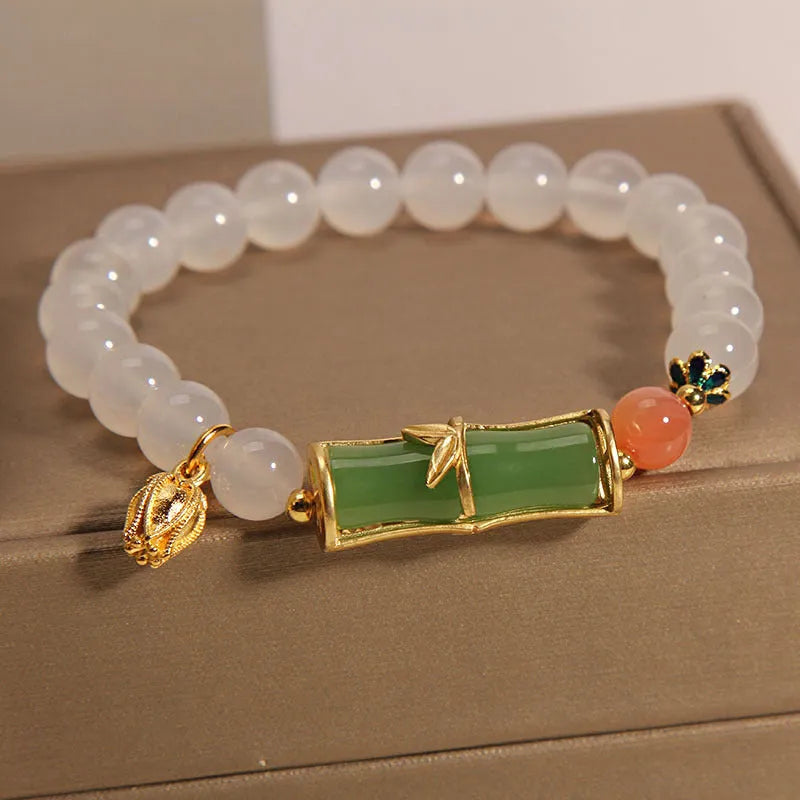 A women's bracelet with a textured jade bamboo bead and a white agate charm on a beaded string.