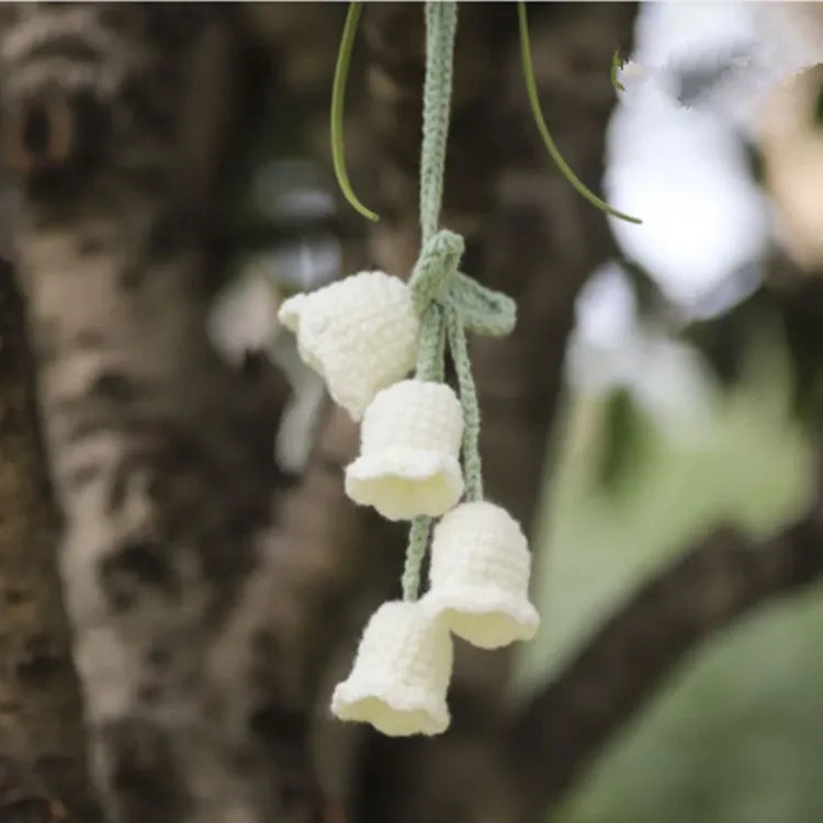 Green and white knitted wool car plant ornament with basin base and hanging rope.