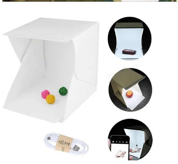 Mini LED folding photo box open with black and white background pads, USB cable, and built-in light for small item photography