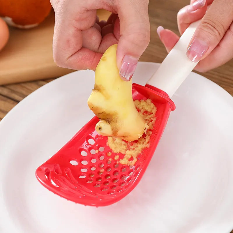 Red and black multifunctional plastic cooking spoon with serrated edges and slotted head on a grey background