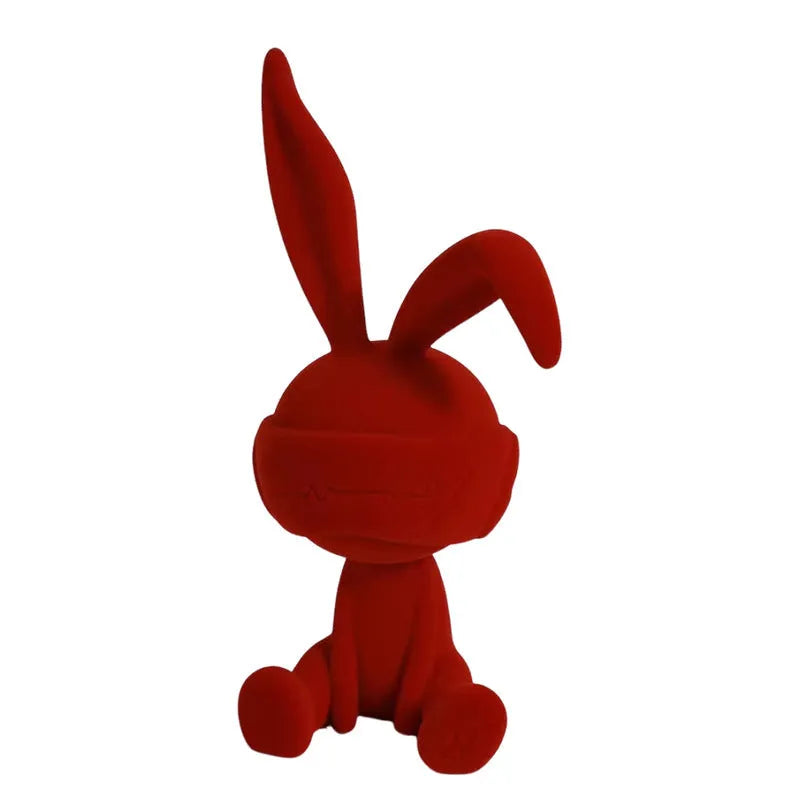 A resin table ornament of a rabbit wearing a suede blindfold, shown in blue, green, and red colour options.