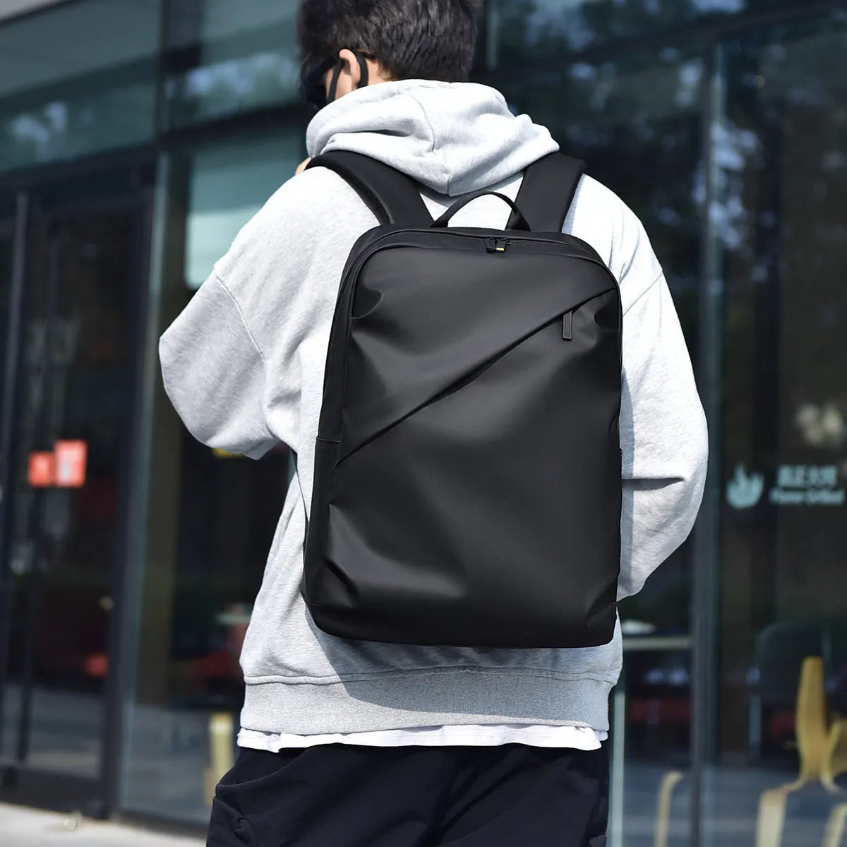 Simple black PU leather backpack with visible sewing thread detailing and large storage capacity