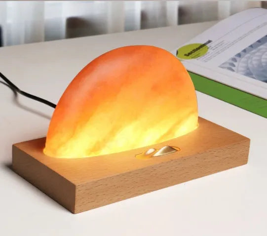 Sunrise Oriental wooden base table lamp with natural crystal salt shade and wireless phone charging pad.