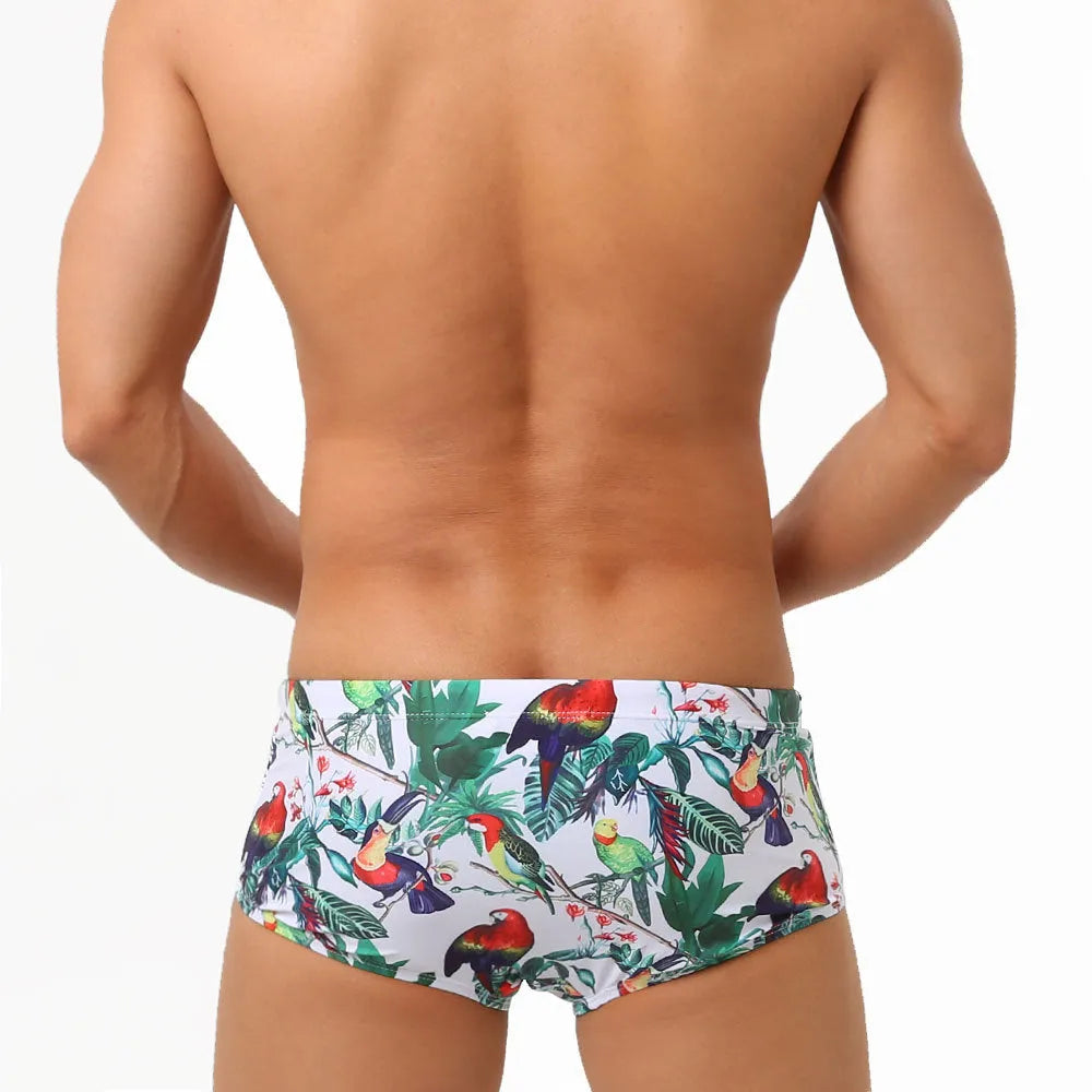 Men's blue swimming trunks with a colourful flowers and birds print, showing the boxer style and cup cover.