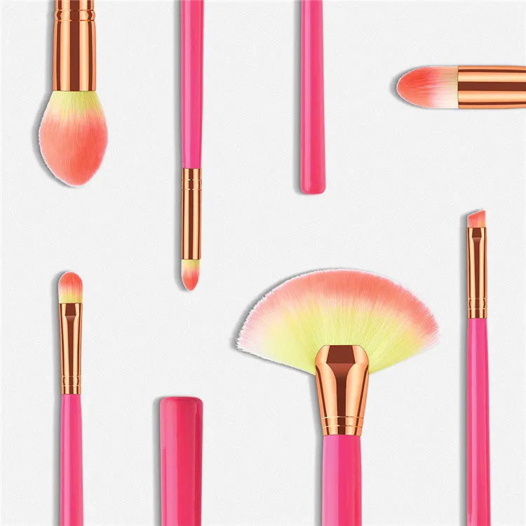 Pink cosmetic makeup brush set with wooden handles and synthetic nylon bristles on a flat surface