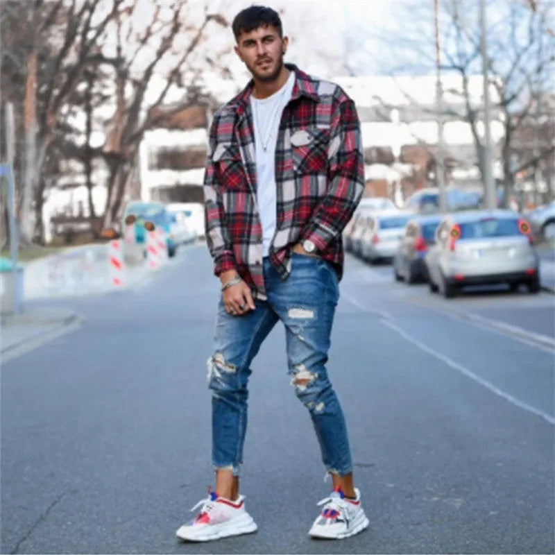Deep blue men's jeans with distressed hole details and five pockets laid flat.