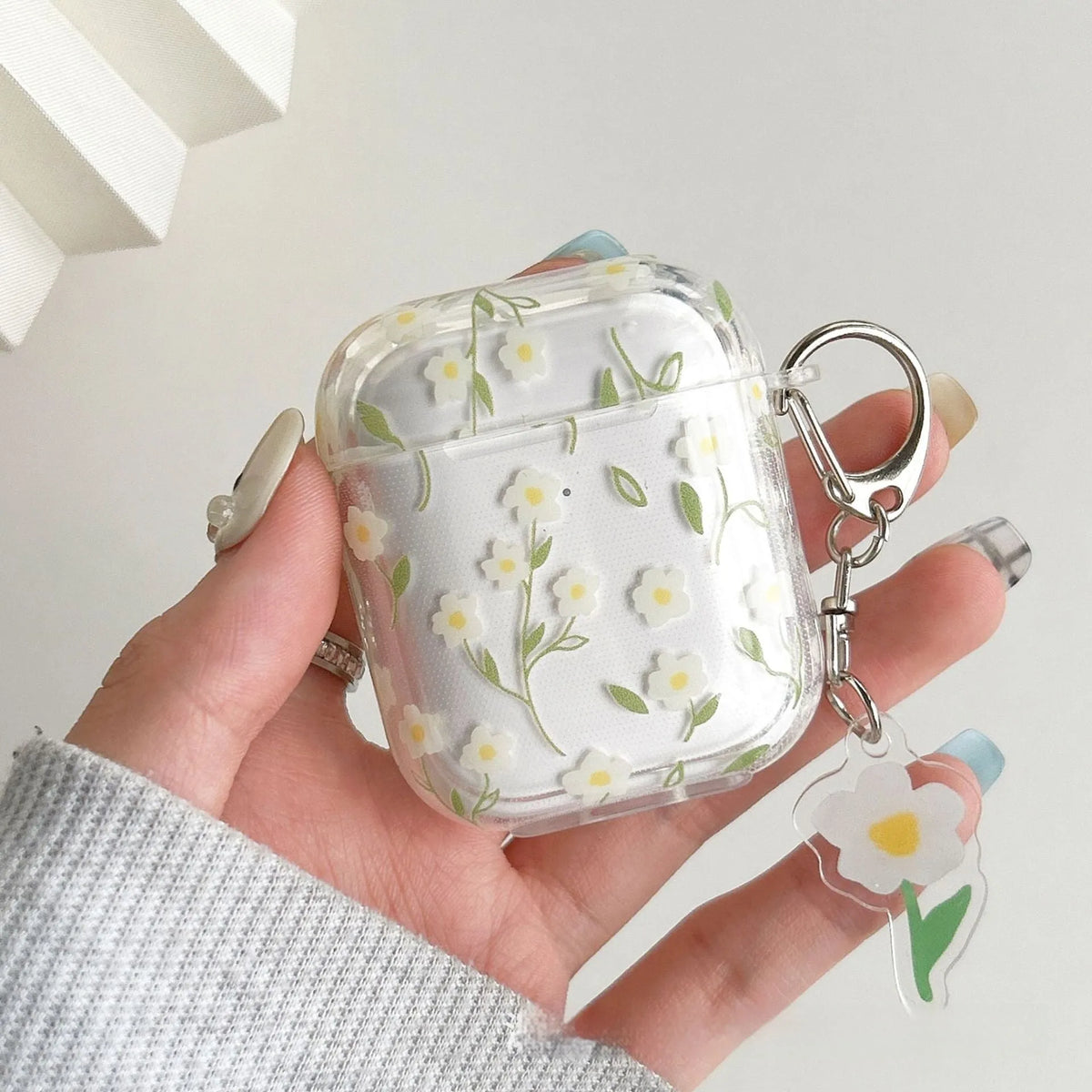 Transparent white floral patterned soft TPU protective case for Apple AirPods on a table.