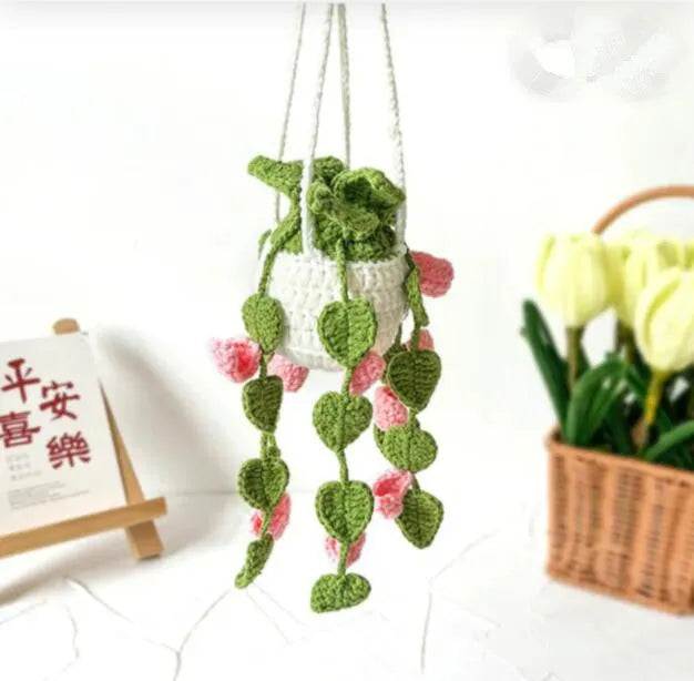 Green and white knitted wool car plant ornament with basin base and hanging rope.