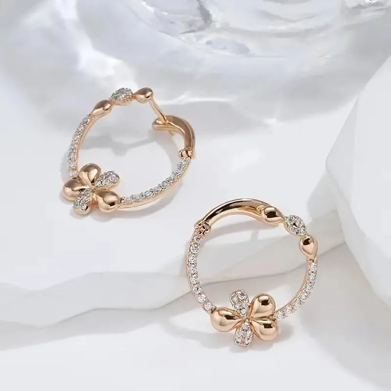 A pair of round gold-coloured hoop earrings with a geometric ring design on a plain background.
