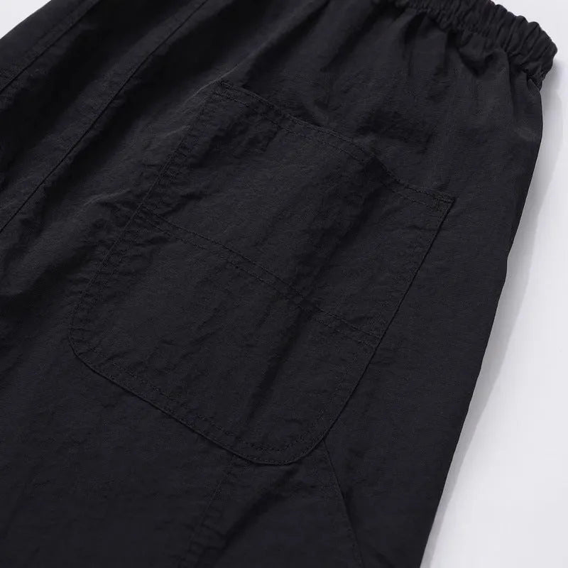 Black men's baggy paratrooper pants with an elastic drawstring waist on a neutral background.