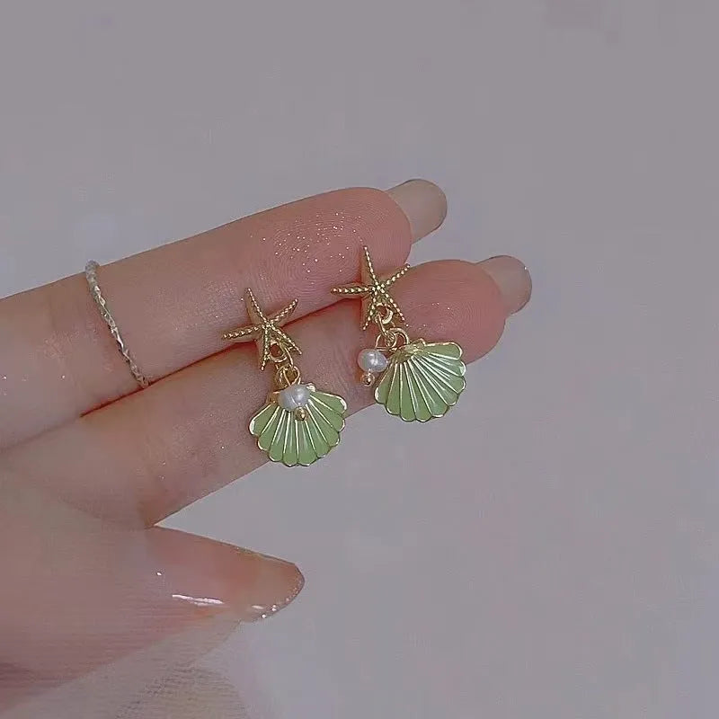 14K gold starfish shell earrings in light green on a white background