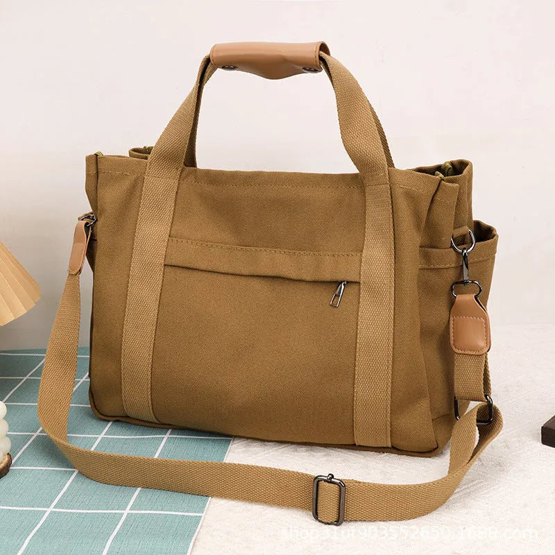 Canvas crossbody tote bag in khaki with open zipper showing internal organiser pockets.