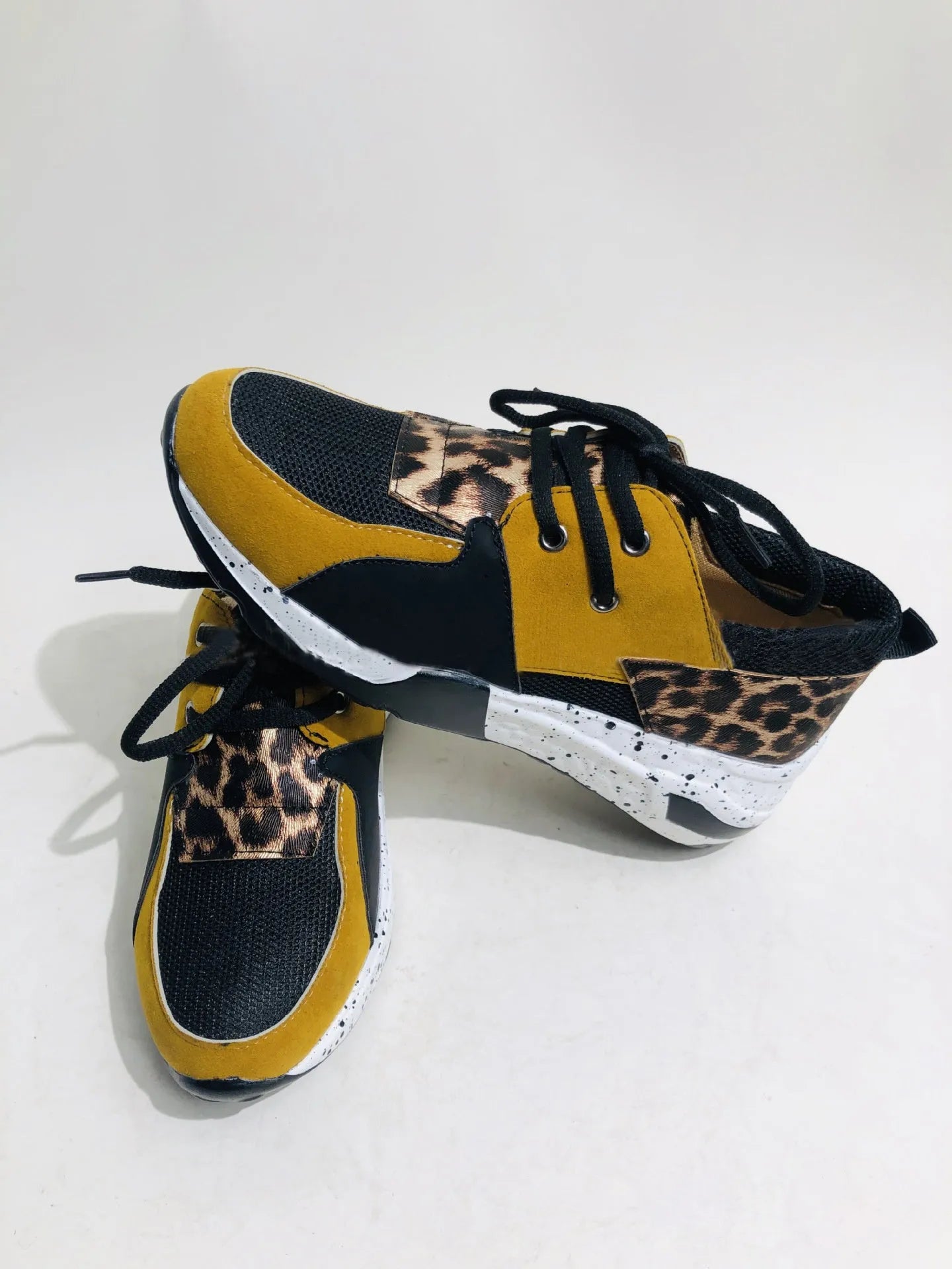 Women's black casual flat sneakers with suede upper and a wedge heel on a breathable fabric base.