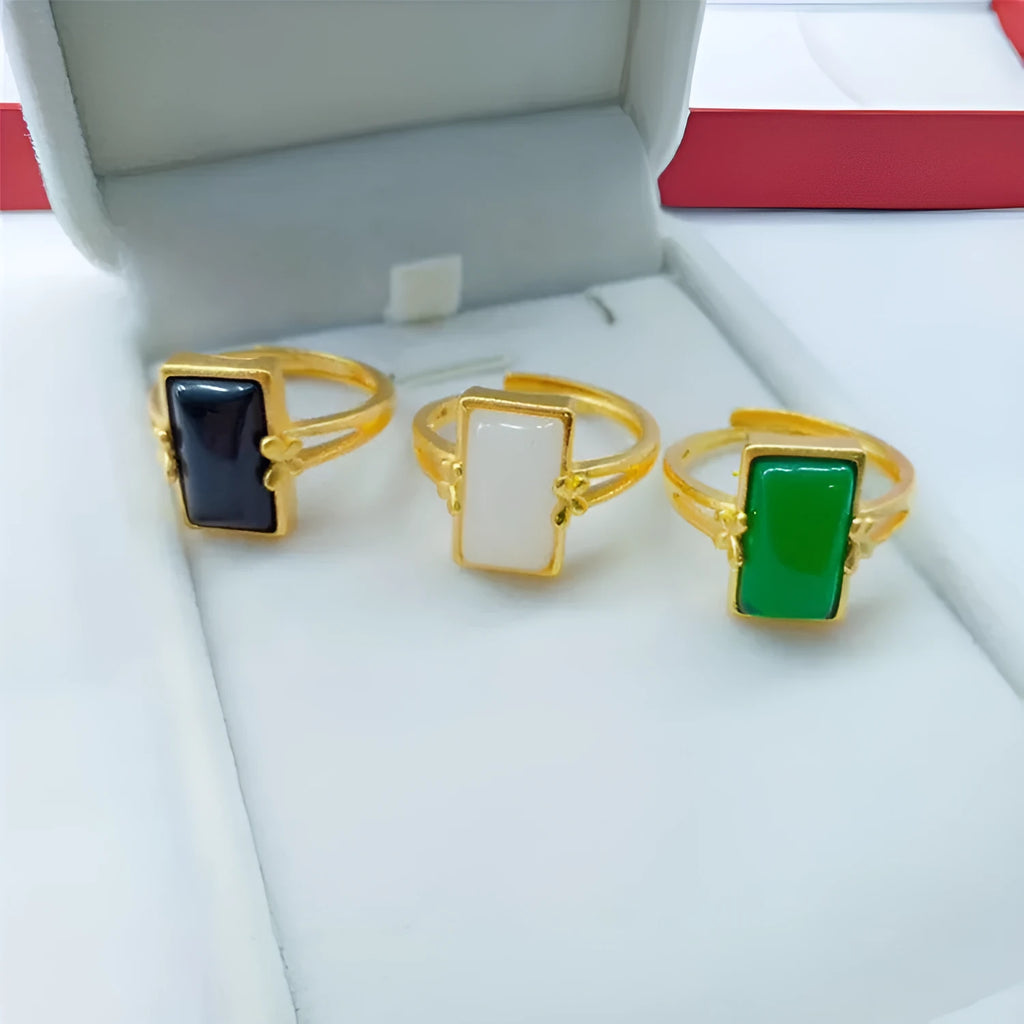 Adjustable gold-plated brass ring with a black electroplated gemstone on a neutral background.