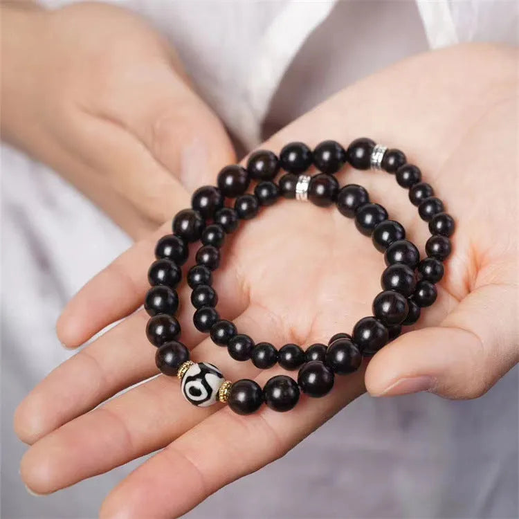 Close-up of a dark ebony wood bracelet with two smooth bead circles on a wrist.