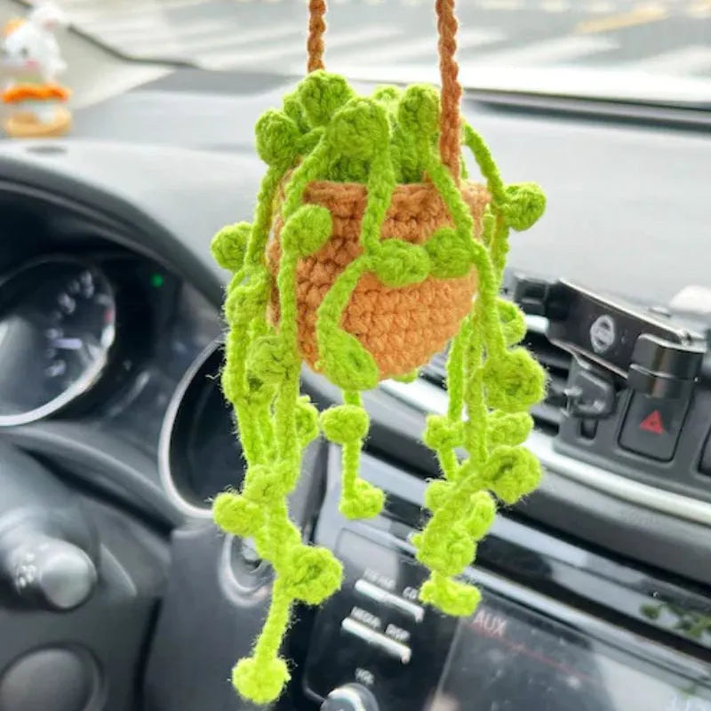 Green and white knitted wool car plant ornament with basin base and hanging rope.