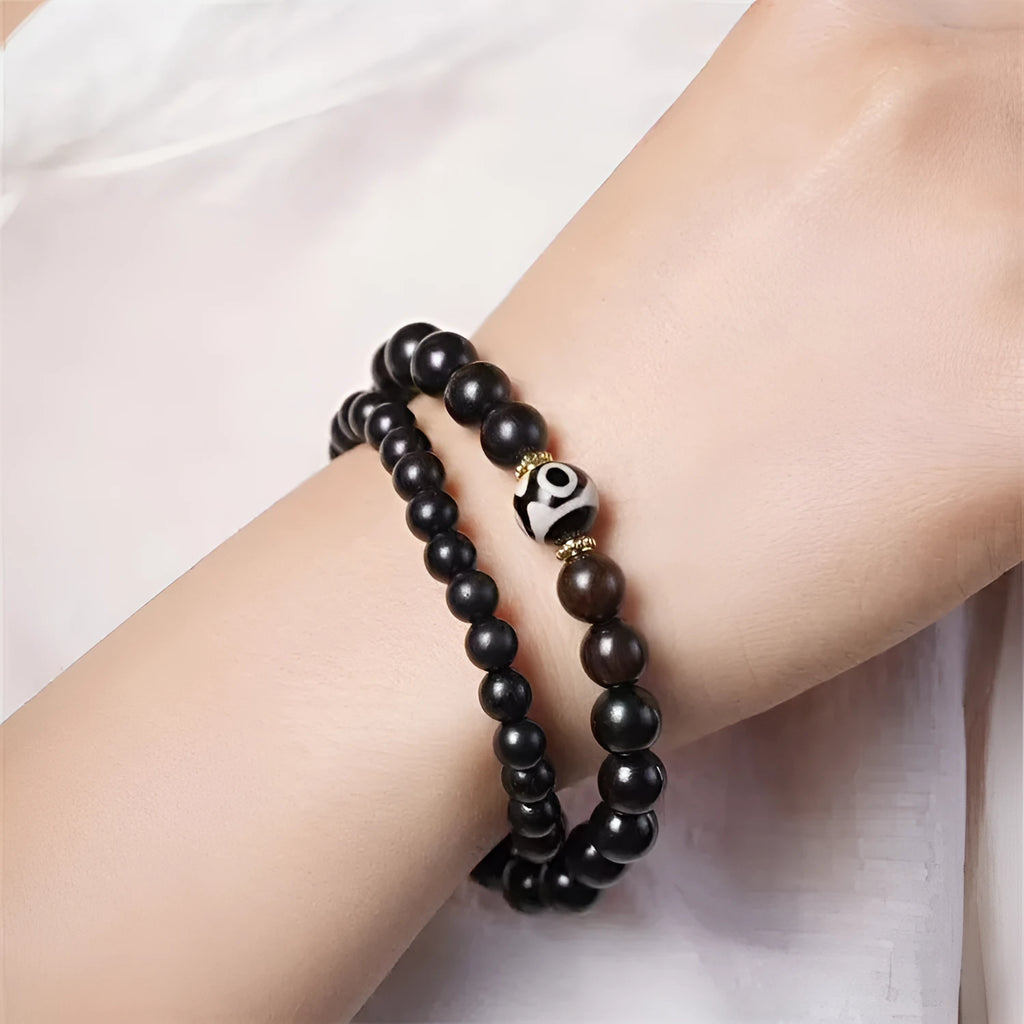 Close-up of a dark ebony wood bracelet with two smooth bead circles on a wrist.