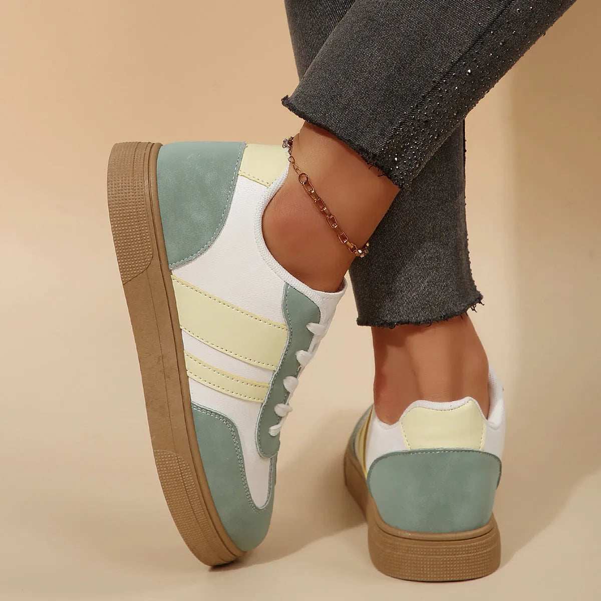 Green women's retro sneakers with cross-strap detail and leather stitching on a white background.