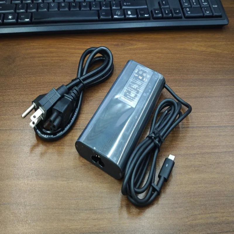 Black 65W USB-C laptop power adapter with UK plug and international travel adapters