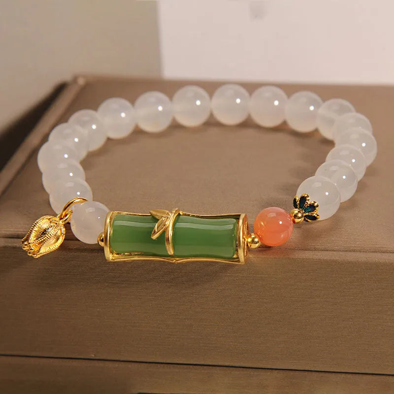 A women's bracelet with a textured jade bamboo bead and a white agate charm on a beaded string.