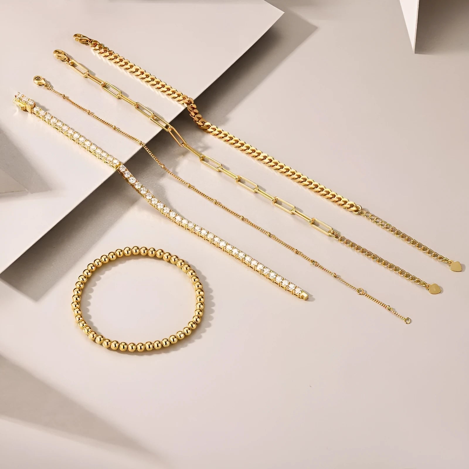 Five stacked S925 silver gold bracelets with round moissanite stones in geometric mosaic design on white background