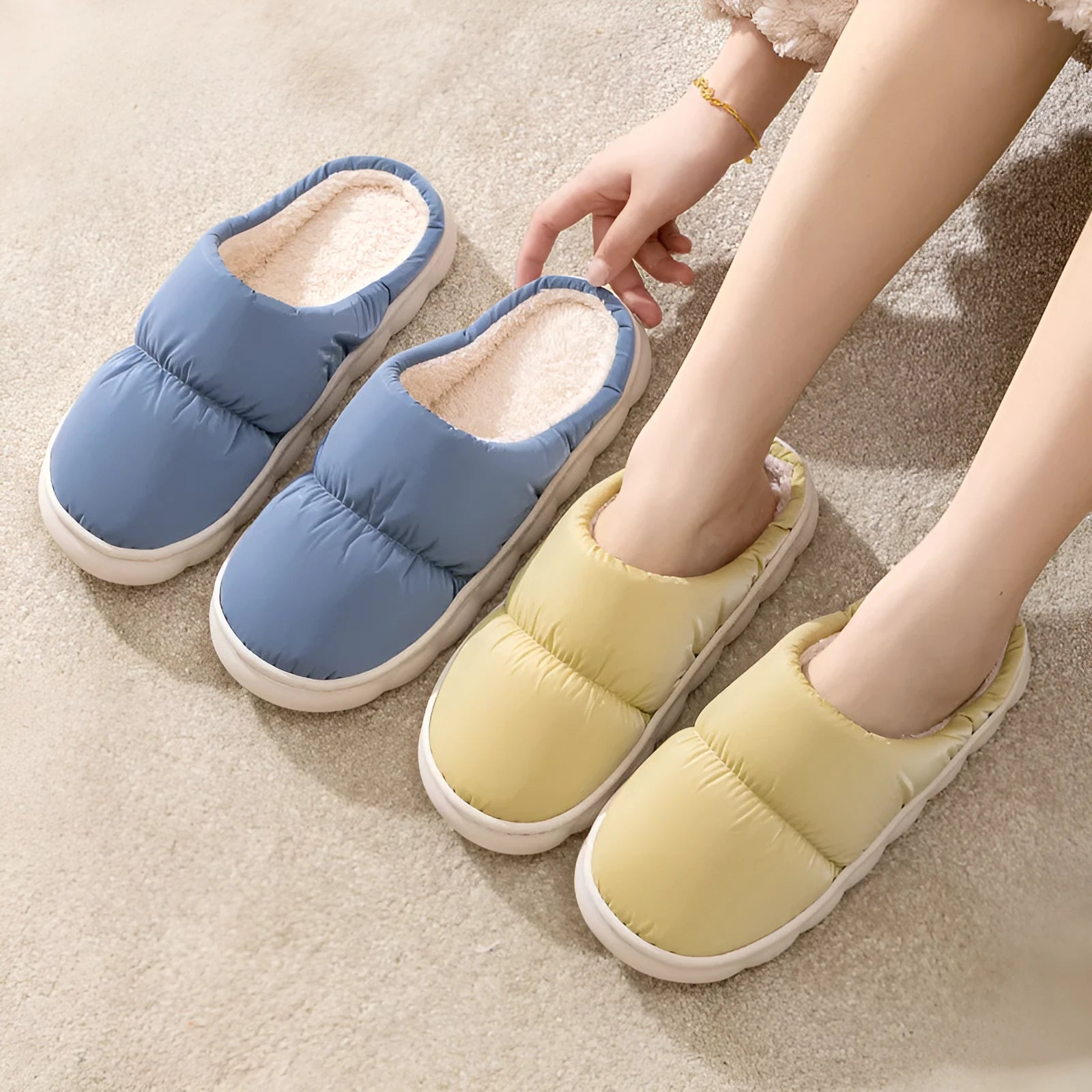 A pair of blue down cotton plush slippers with a thick rubber sole and artificial leather upper, shown on a wooden floor.