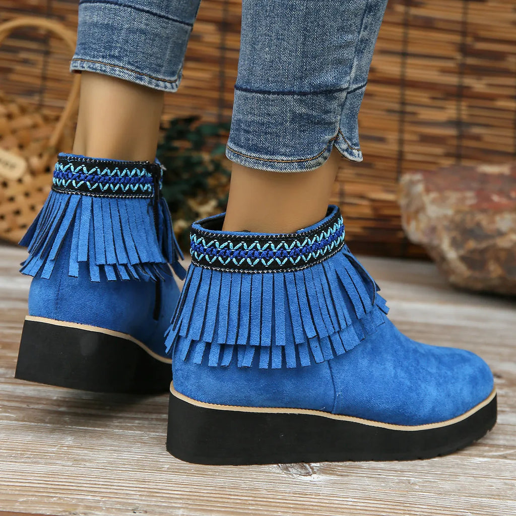Women's suede ankle boot with wedge heel, side zipper, tassel detail, and thick rubber sole in three colour options.