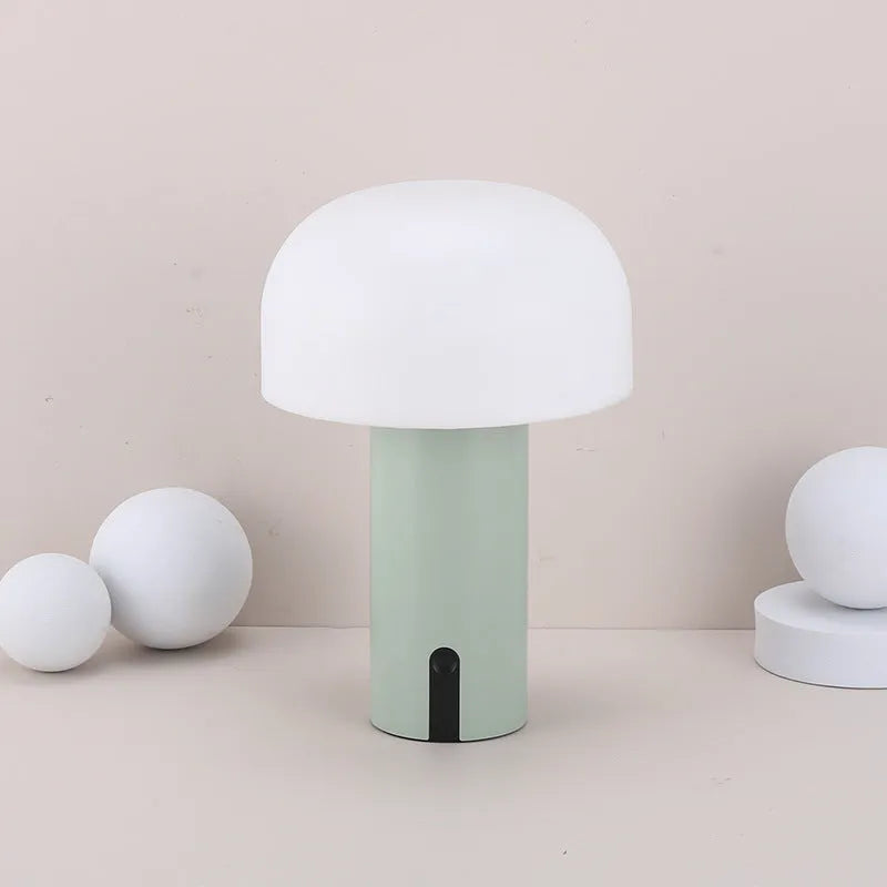 Decorative LED mushroom night light in green with warm white glow on a bedside table
