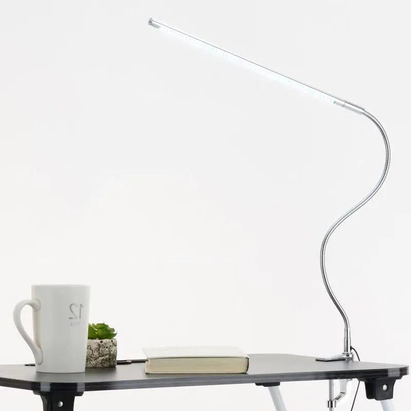 Silver LED clip-on table lamp with long arm extended, showing aluminium alloy construction and USB cable.