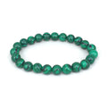 Malachite green and black matte 8mm round bead elastic strand bracelet on a neutral background