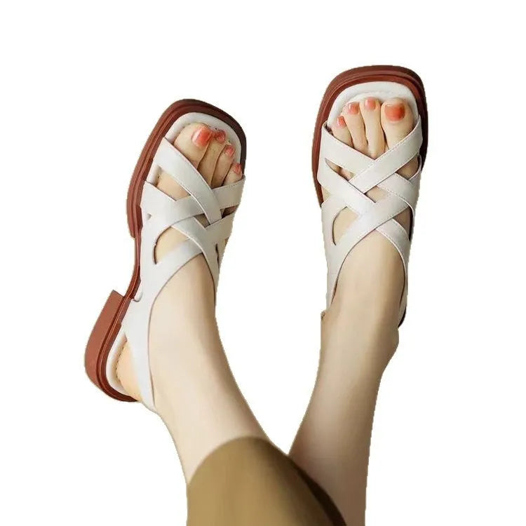 Women's glossy patent leather square toe sandals with winding tape fastening on a neutral background.
