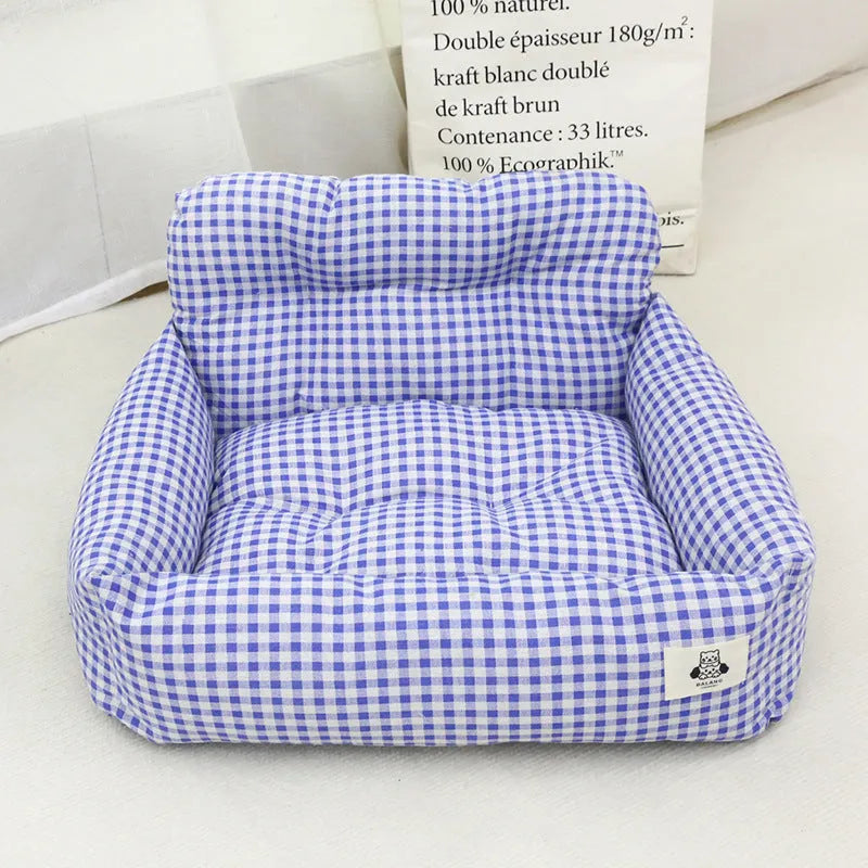 Blue plaid portable dog car bed nest with raised sides, shown on a vehicle seat.