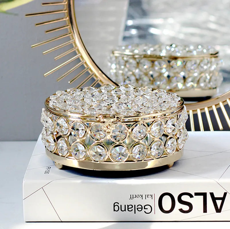 Transparent crystal glass jewelry storage box with ornate French gold metal frame.