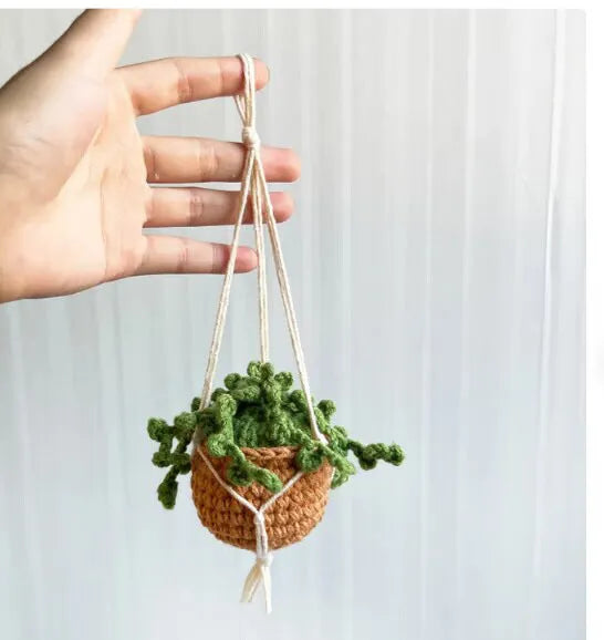 Green and white knitted wool car plant ornament with basin base and hanging rope.