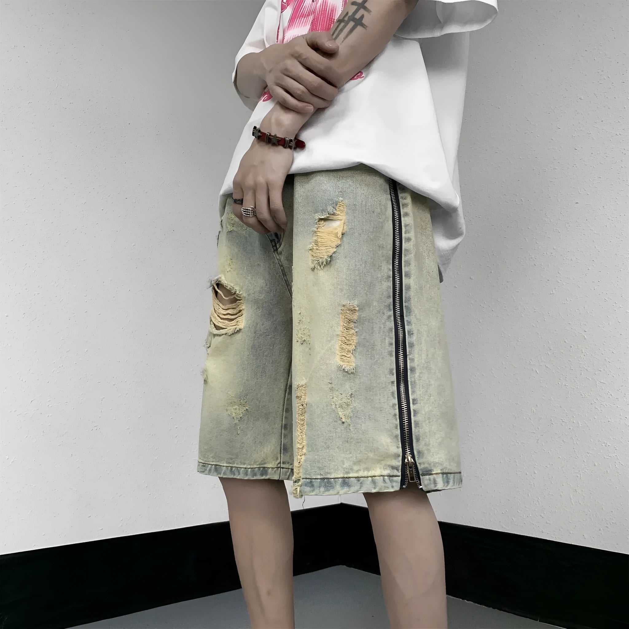 Men's blue denim shorts with mud-wash finish and ripped distressing on a hanger