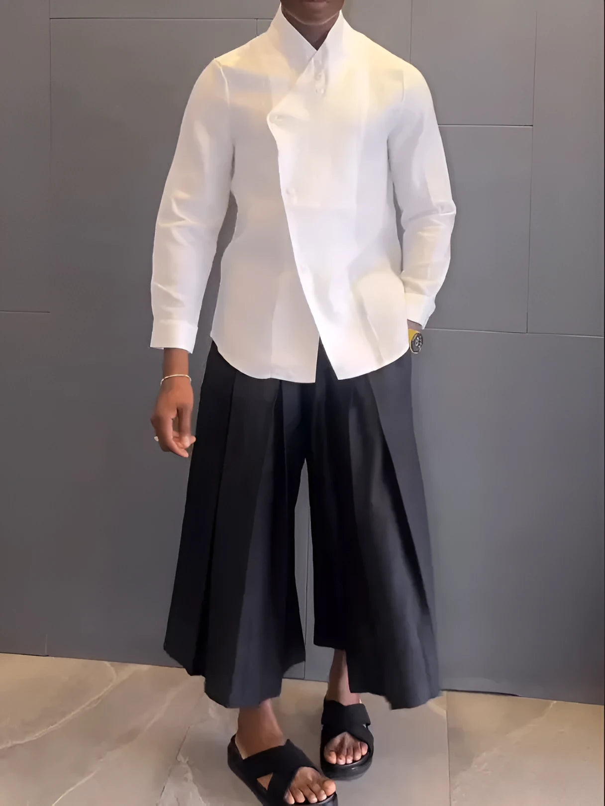 White asymmetric long sleeve shirt and black pleated trousers co-ord set on a hanger