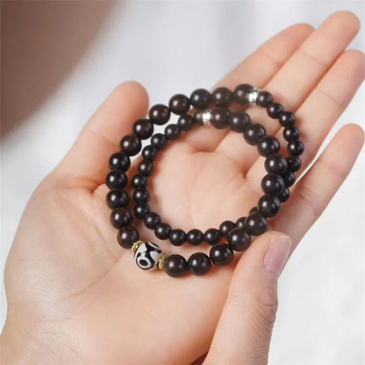 Close-up of a dark ebony wood bracelet with two smooth bead circles on a wrist.