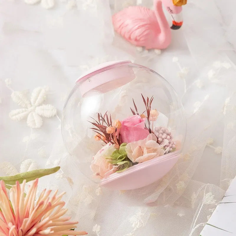 Pink preserved rose ornament gift with optional Bluetooth audio base on a wooden table.