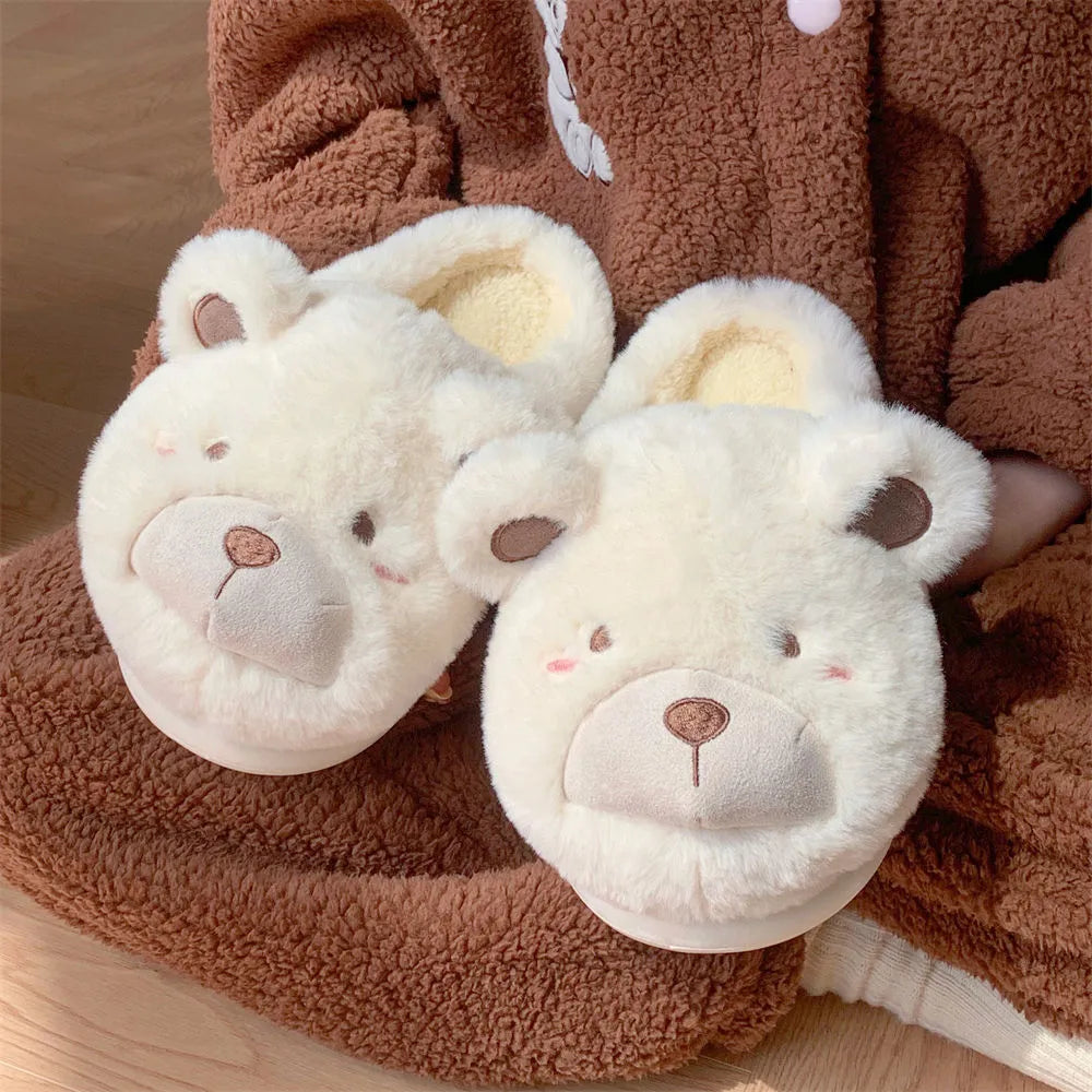 A pair of milky white baotou slippers with suede uppers and a cartoon pattern, showing the round toe shape.