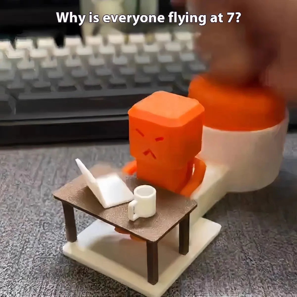 Orange plastic decompression toy with a table-turning mechanism on a desk.