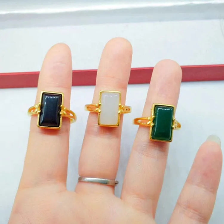Adjustable gold-plated brass ring with a black electroplated gemstone on a neutral background.