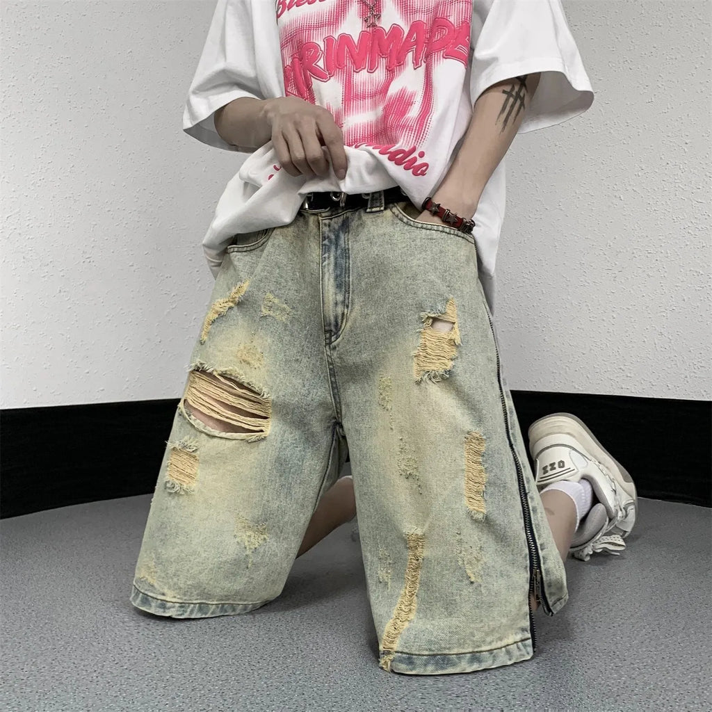 Men's blue denim shorts with mud-wash finish and ripped distressing on a hanger