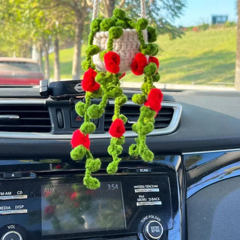 Green and white knitted wool car plant ornament with basin base and hanging rope.