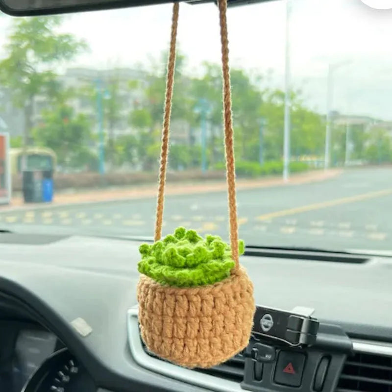 Green and white knitted wool car plant ornament with basin base and hanging rope.