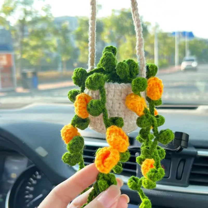 Green and white knitted wool car plant ornament with basin base and hanging rope.