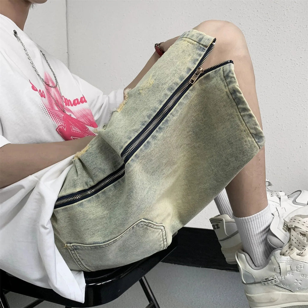 Men's blue denim shorts with mud-wash finish and ripped distressing on a hanger