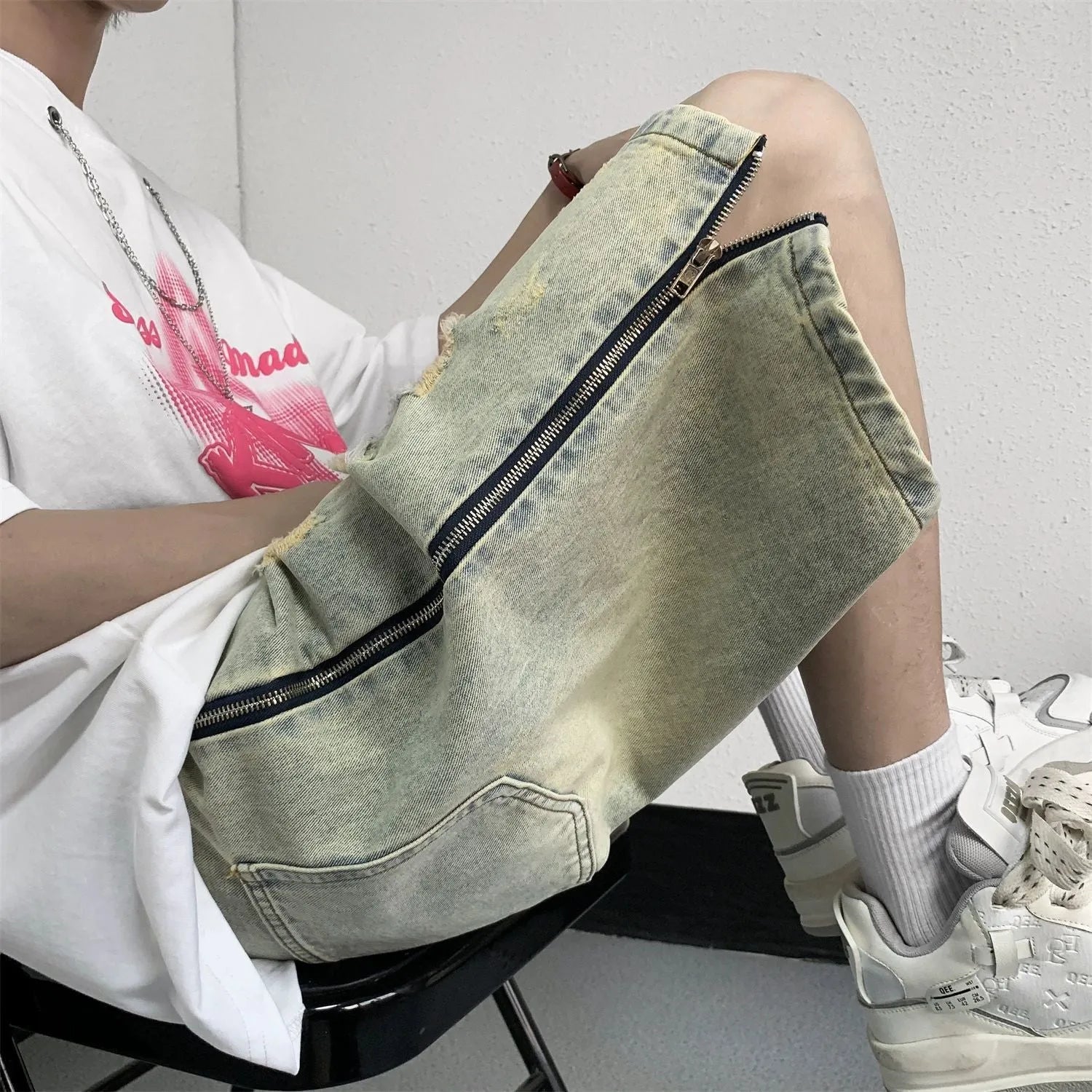 Men's blue denim shorts with mud-wash finish and ripped distressing on a hanger