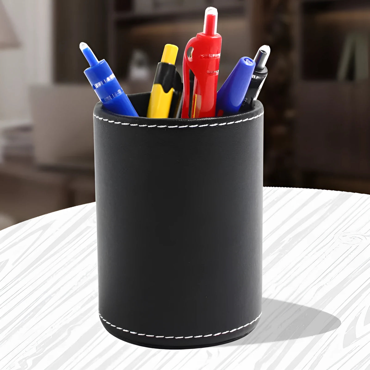Small round black leather pen container on a desk