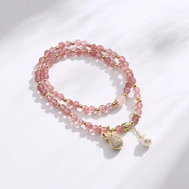 Women's geometric strawberry quartz crystal wallet bracelet on a wrist.